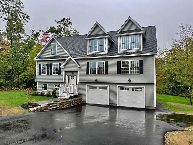 Front exterior of newly built cape with dormers and two-car garage