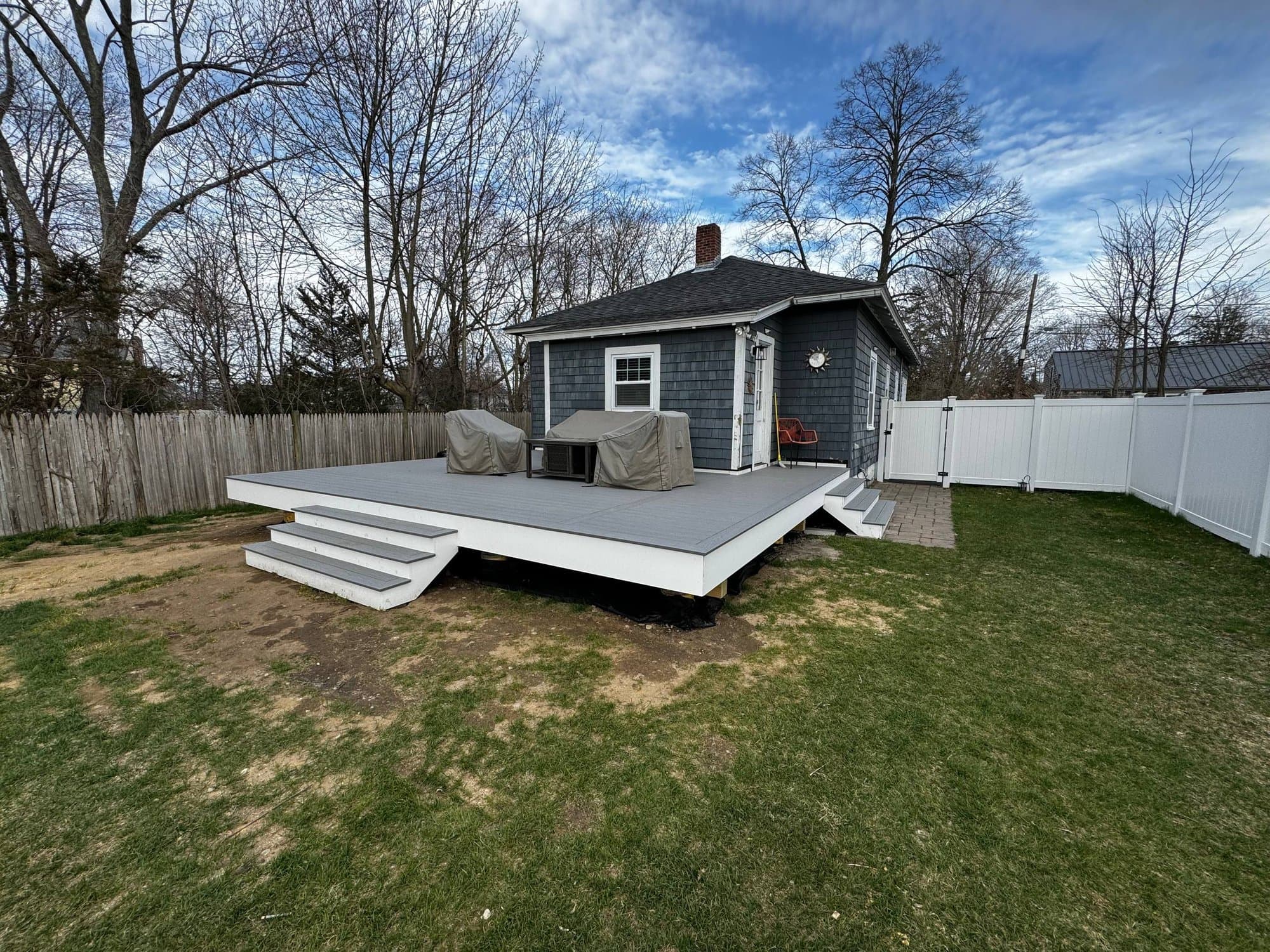 Daytime view of the finished deck, white skirting, and wide stairs down to the lawn