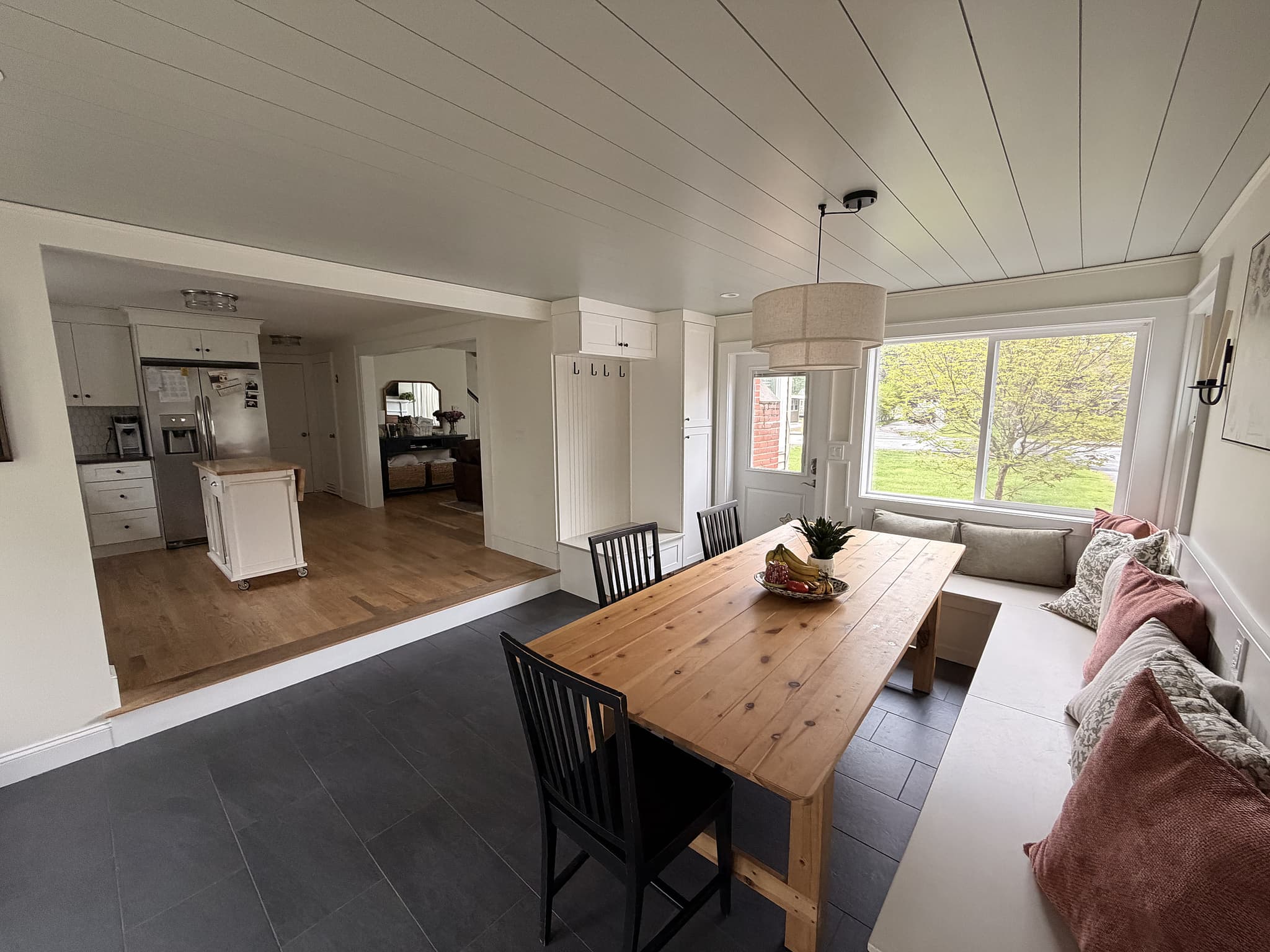 Dining room added onto a Dover, NH home, with shiplap ceiling, custom built-in bench seating, and an open view through to the kitchen
