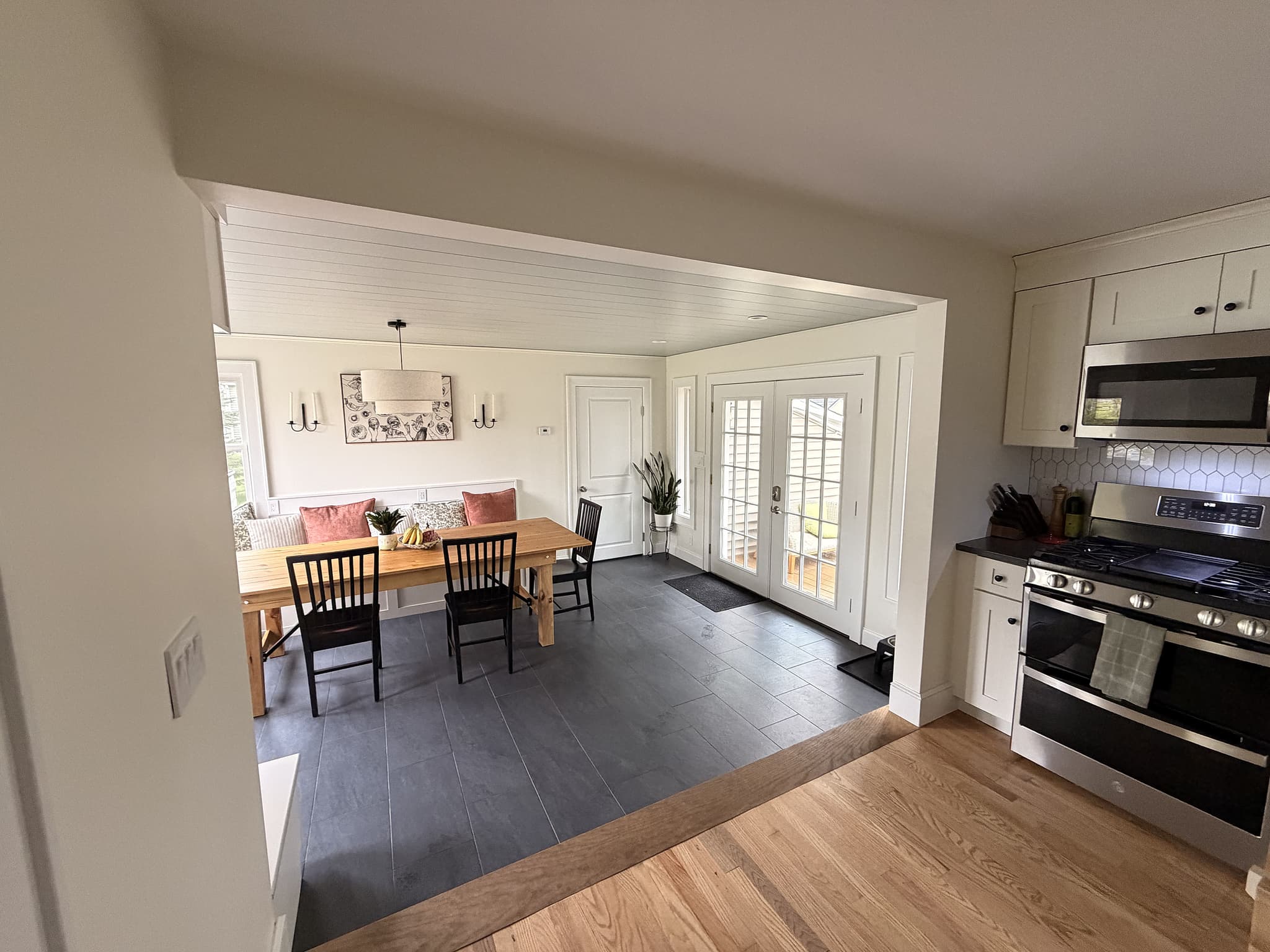View from the kitchen through the enlarged opening into the new dining space, with French doors at the back and built-in bench seating along the wall
