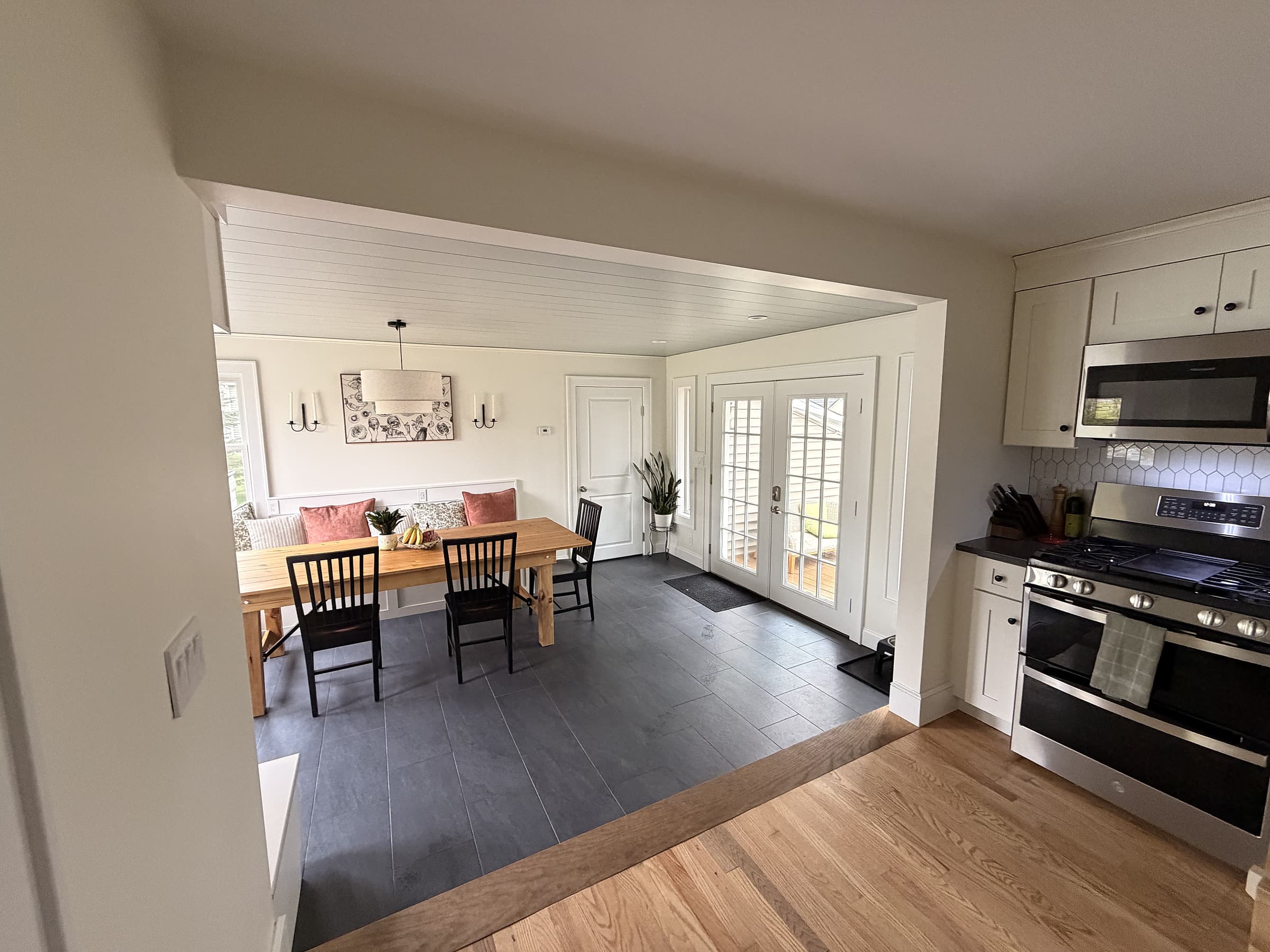 View from the kitchen through the enlarged opening into the new dining space, with French doors at the back and built-in bench seating along the wall