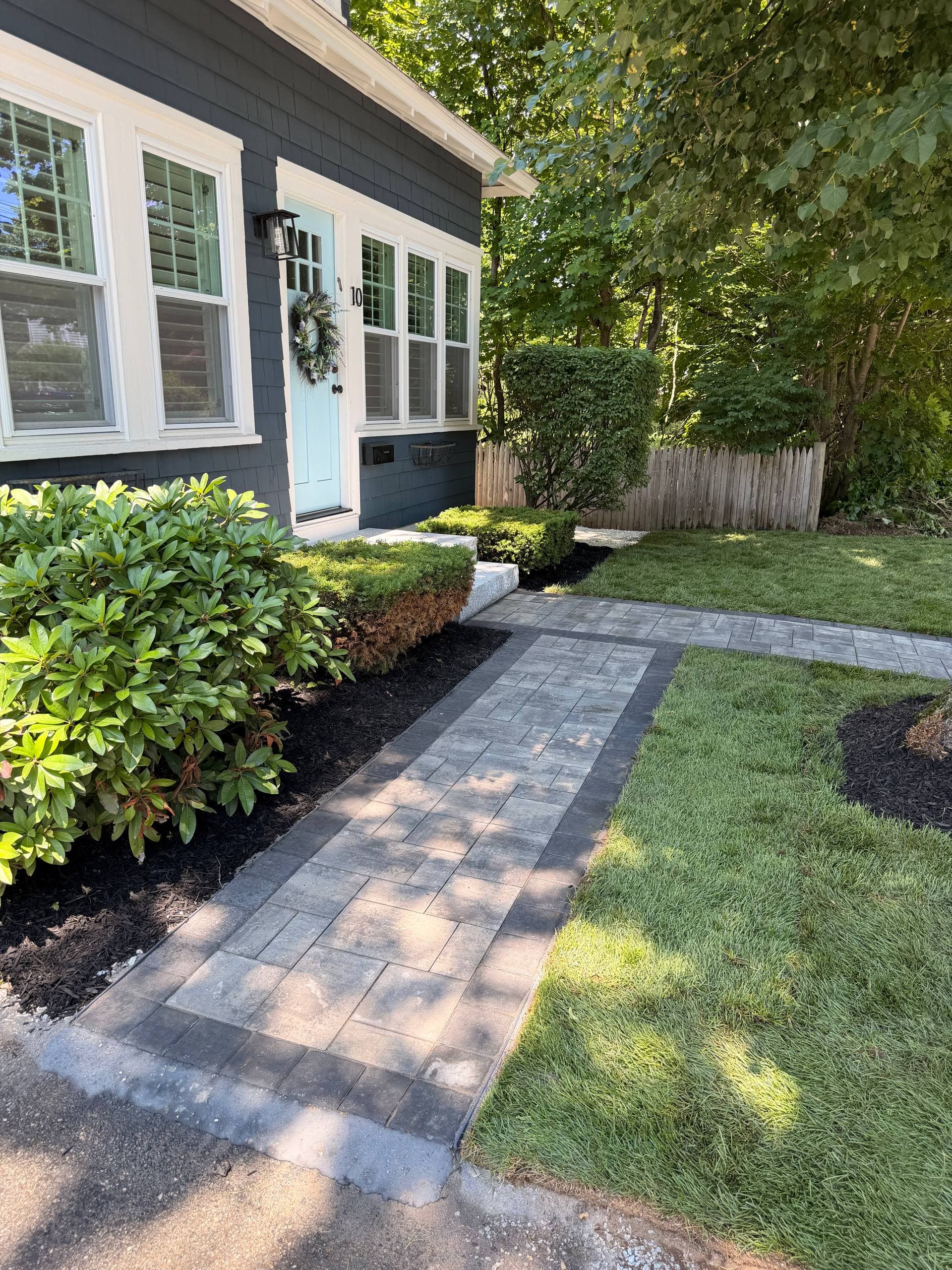 Completed paver walkway with Coal border running to the granite steps, bordered by fresh sod and mulched plantings
