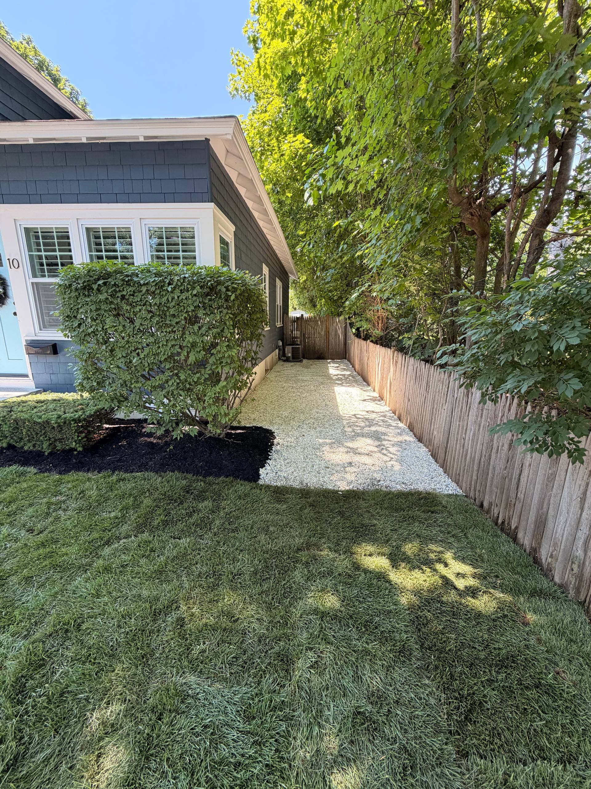 Washed-stone path running along the side yard to the back gate, edged by new sod