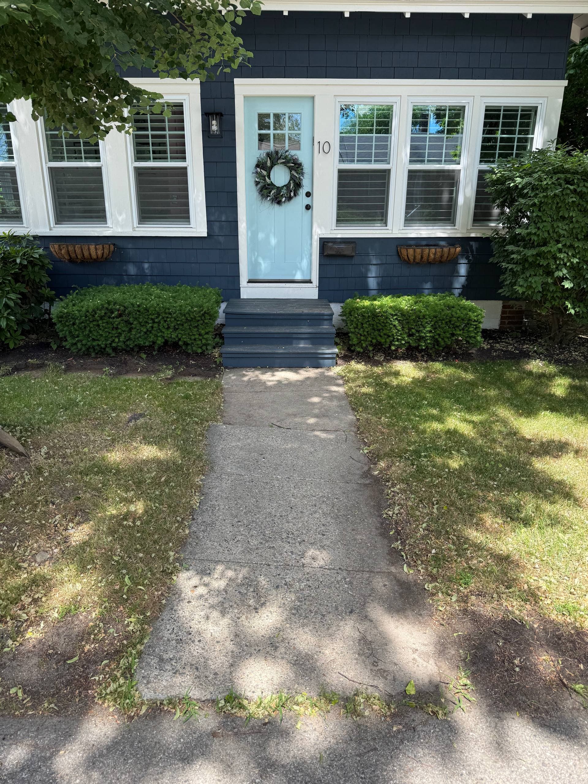 Original front entry before the rebuild — cracked concrete walkway and worn painted-wood steps