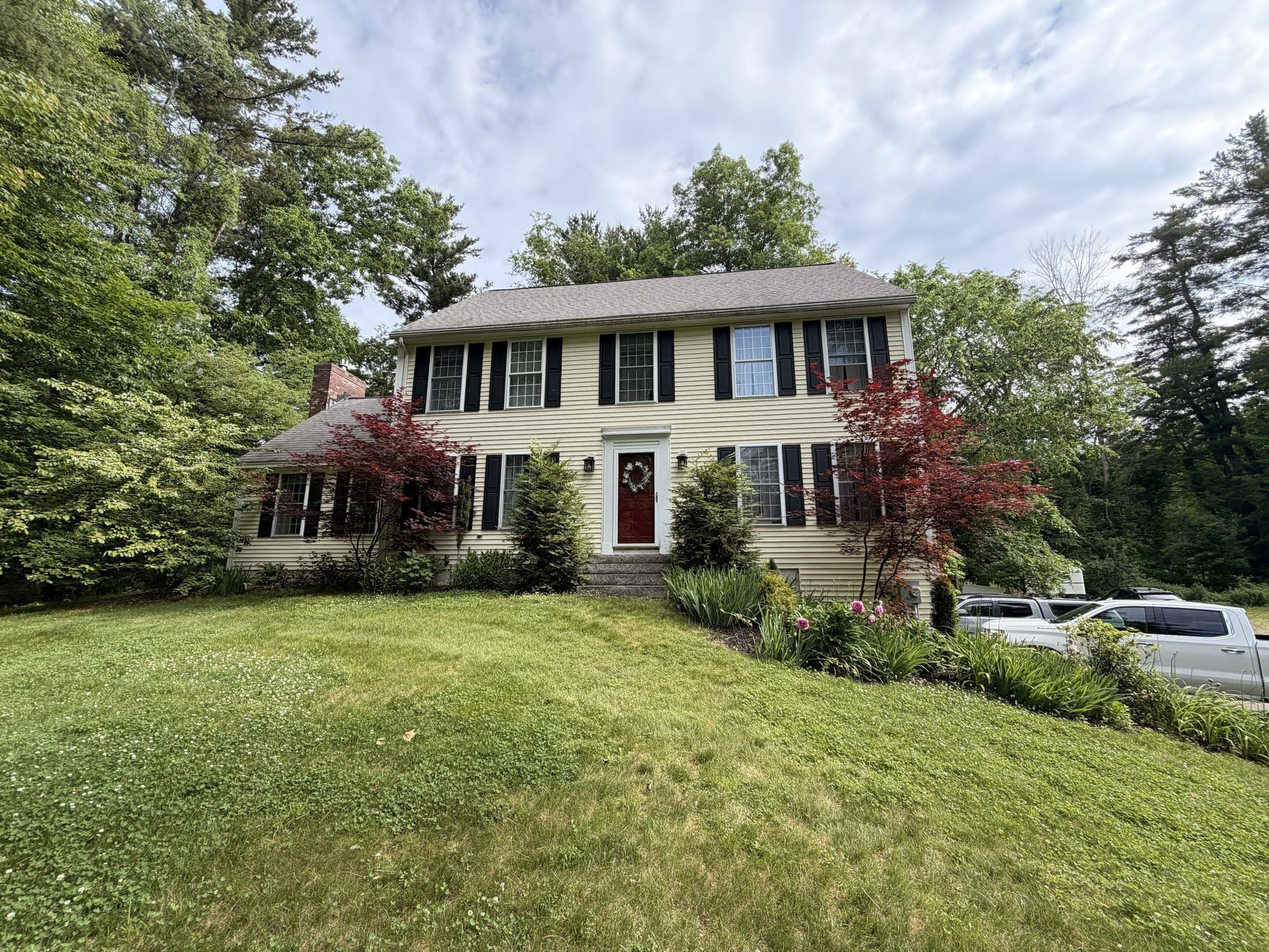 Front elevation of the colonial before the roof replacement, with the original worn asphalt shingles