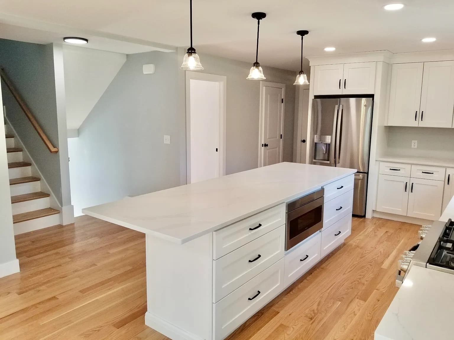 Open-concept kitchen with large quartz island and pendant lighting