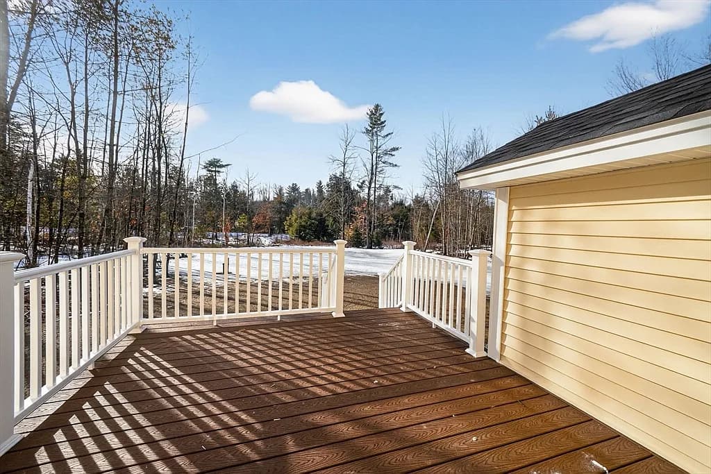 Rear deck with white railings overlooking wooded backyard