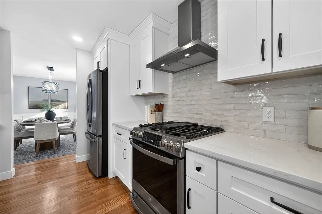 Kitchen gas range with stainless vent hood and tile backsplash