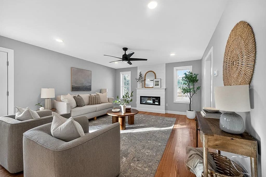 Staged living room with shiplap fireplace wall and hardwood flooring