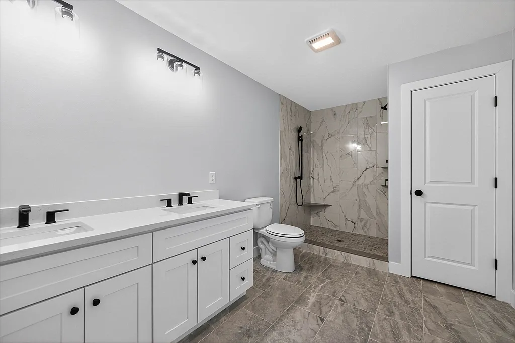 Primary bathroom with double vanity and walk-in tile shower