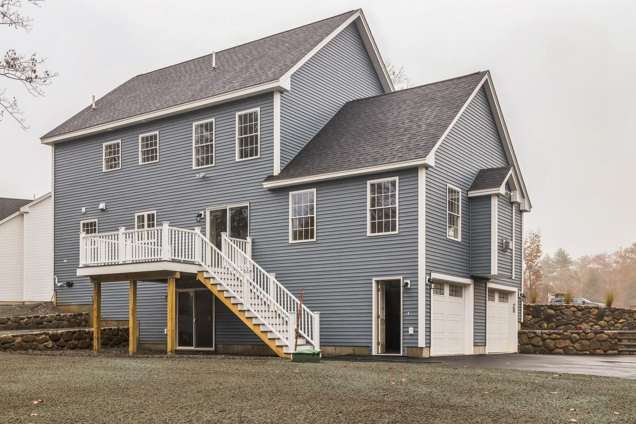 Rear exterior with deck, stairs, and two-car garage