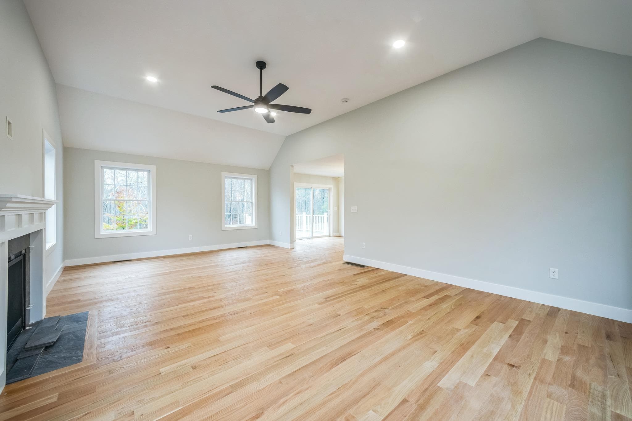 Family room with vaulted ceiling, stone fireplace, and large windows