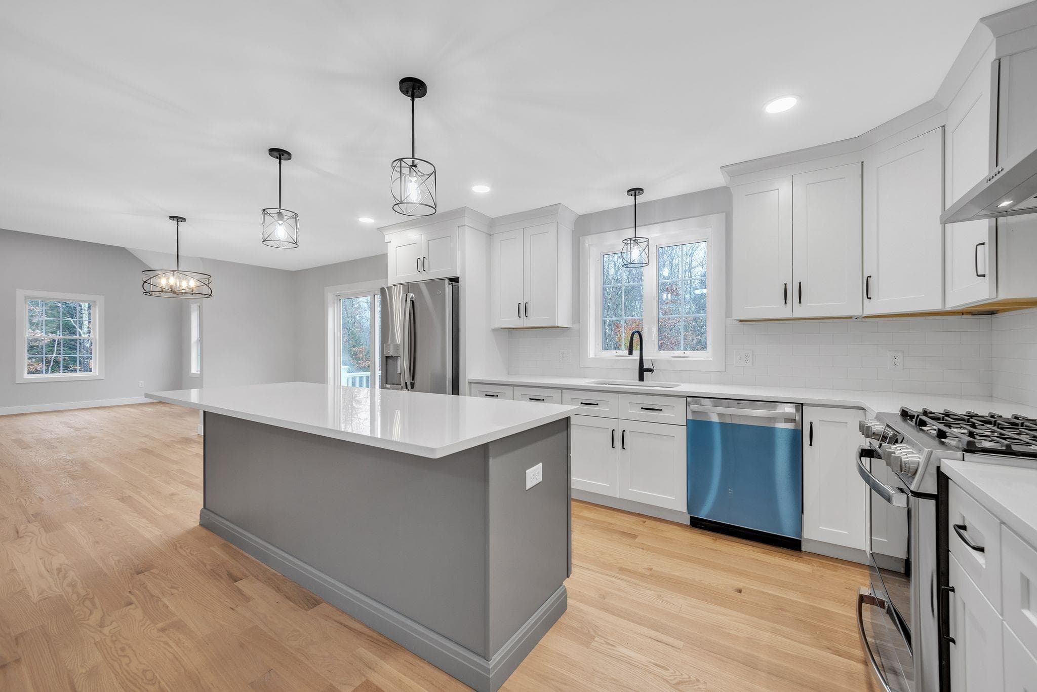 Kitchen with gray island, quartz countertops, and stainless appliances