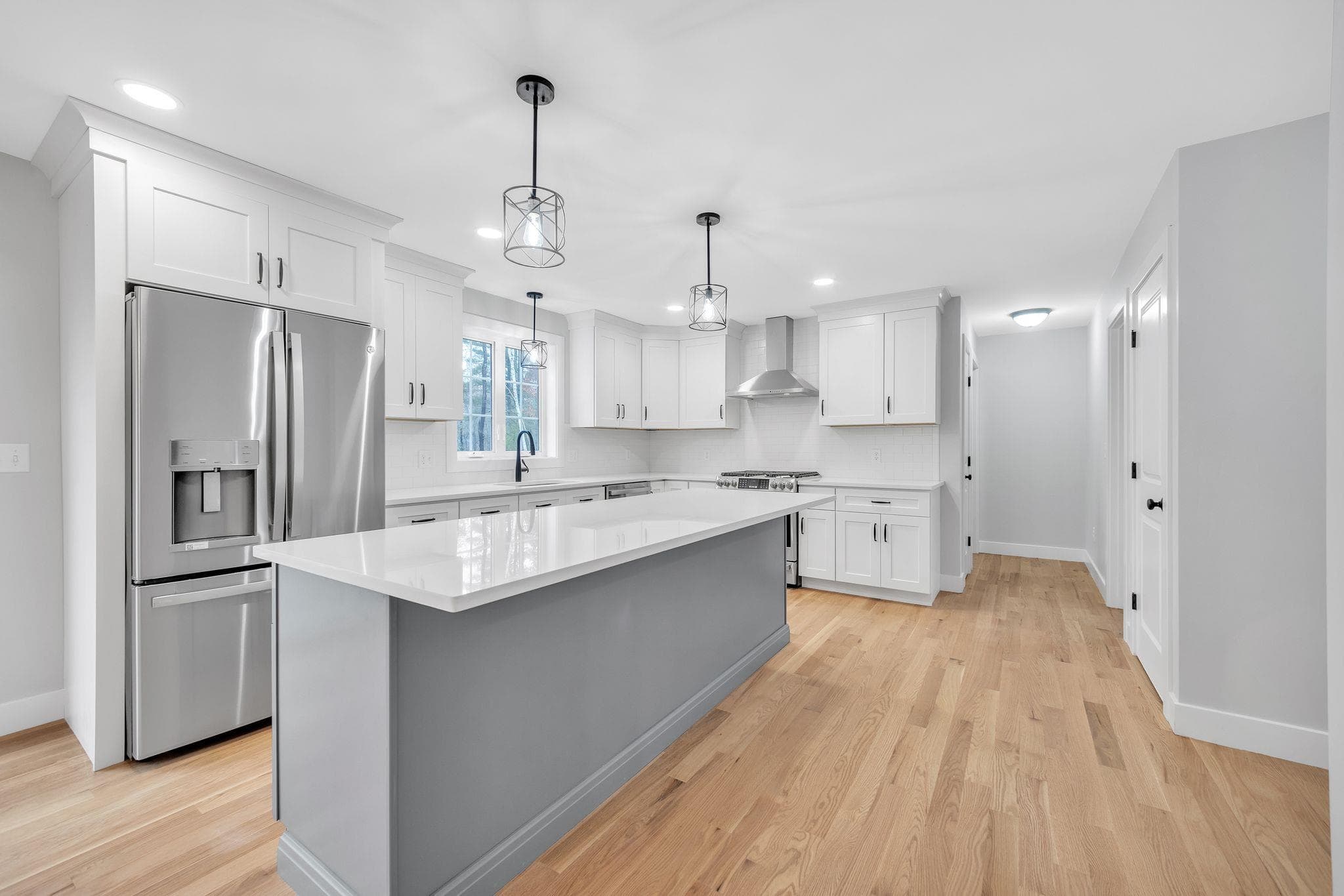 Kitchen with gas range, stainless vent hood, and tile backsplash